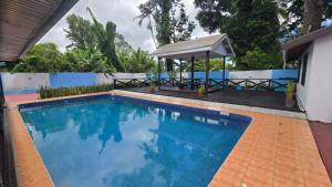 a swimming pool with a gazebo next to a house at Paradise Pacifica in Pacific Harbour