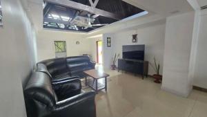 a living room with black leather furniture and a flat screen tv at Paradise Pacifica in Pacific Harbour