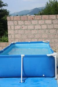 a blue swimming pool in front of a brick wall at Sunny Home in Gandzakʼar