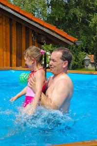a man and a little girl in a swimming pool at Almerhof - Waldferienhof Almer in Zwiesel