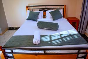 a bed with white sheets and green pillows at theSuperblane Resort in Sagana