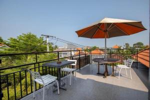 a balcony with two tables and an umbrella at Lushy Hostel Canggu in Canggu