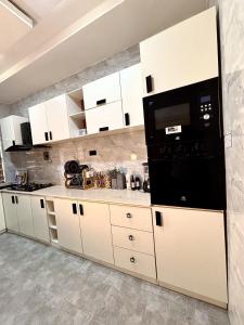a kitchen with white cabinets and a black microwave at Modern getaway in Ajah in Lekki