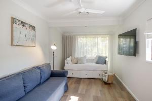 a living room with a blue couch and a bed at Narrawallee Nirvana in Narrawallee