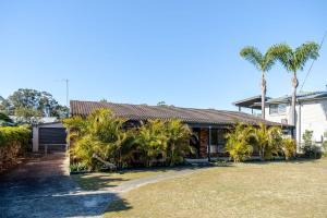 a house with palm trees in front of it at Narrawallee Nirvana in Narrawallee