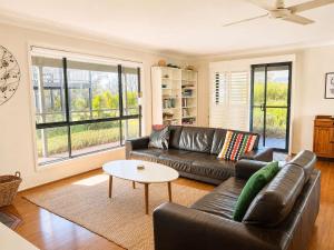 a living room with a leather couch and a table at Bawley Beach Bungalow in Bawley Point