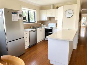 a kitchen with white cabinets and a stainless steel refrigerator at Bawley Beach Bungalow in Bawley Point