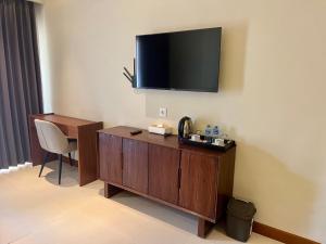 a hotel room with a desk and a television on the wall at Taman Agung Hotel in Sanur