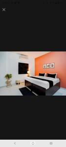 a bedroom with a large bed with an orange wall at New Stay Hotel in Gurgaon