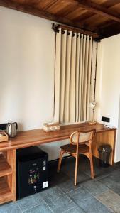 a wooden desk with a chair next to a window at Mango Garden Villas in Sekongkang Bawa