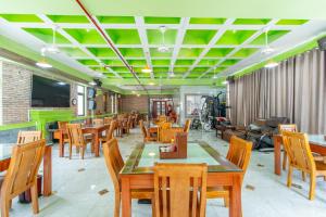 a restaurant with wooden tables and chairs and green ceilings at Apogee Hotel in Ho Chi Minh City