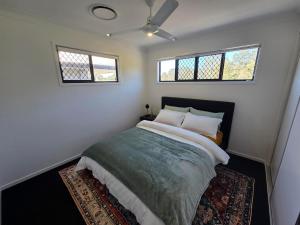 a bedroom with a bed with two windows and a rug at Private Room with Queen Bed & Bathroom in Bellbird Park +5 photos