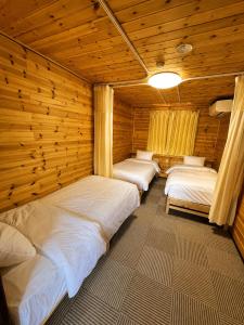 a row of beds in a room with wooden walls at Meteor Garden in Hakuba