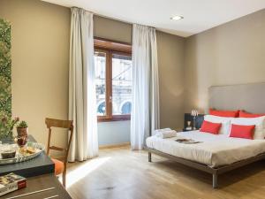 a bedroom with a bed with red pillows and a table at Monti First in Rome