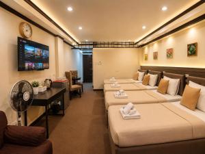 a hotel room with four beds and a flat screen tv at Amax Inn Makati in Manila