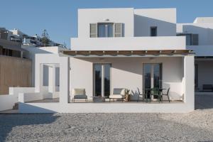 a white house with a patio with chairs and a table at Estia Villas Naxos in Naxos Chora