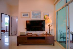 a living room with a large television and a desk at Ped pool villa in Buriram