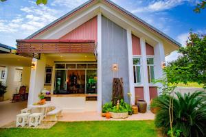 a house with a patio with a table and chairs at Ped pool villa in Buriram