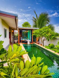 a pool in the backyard of a house with green plants at Ped pool villa in Buriram