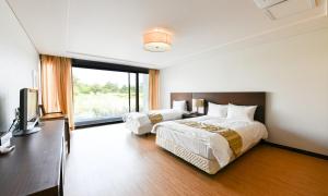 a hotel room with two beds and a television at Jeju Tameus Golf & Village in Hahwajŏn +19 photos