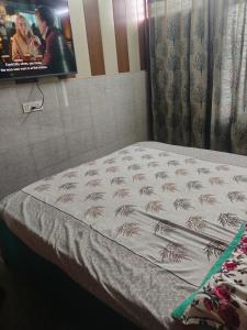 a bed in a room with a tv on the wall at Osween Guest House in Srinagar