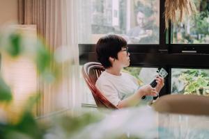 a woman sitting in a chair holding a cell phone at Tree House Café & Homestay in Tongluo