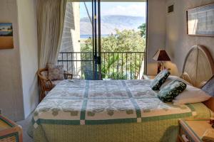 a bedroom with a bed with a view of a balcony at Kauhale Makai 230 in Kihei