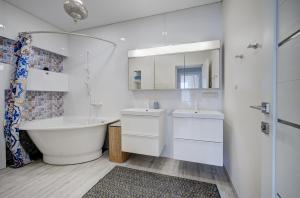 a white bathroom with a tub and a sink at Pavilnis house in Vilnius