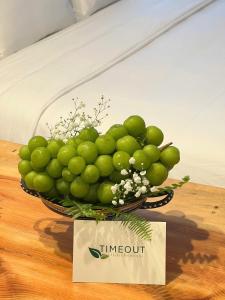 a basket of green fruit on a table with a sign at TimeOut Dalat Boutique Hotel in Khu Chi Lăng