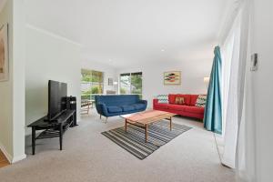 a living room with a red couch and a blue chair at Serrell by the Sea in Inverloch