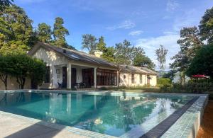 a swimming pool in front of a house at Jetwing Hoffmann Bungalow in Welimada