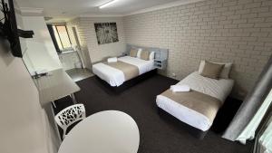 a bedroom with two beds and a brick wall at Jefferys Motel in Toowoomba