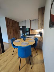 a kitchen with a wooden table and blue chairs at Apartmán Vyhne in Vyhne +5 photos