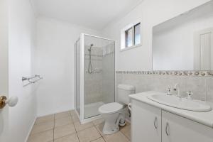 a white bathroom with a toilet and a sink at Serrell by the Sea in Inverloch +12 photos