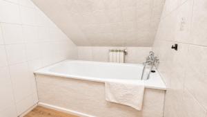 a white bath tub in a white tiled bathroom at Hotel Ukiel Wellness & SPA in Olsztyn +43 photos