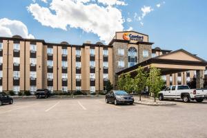 a hotel with cars parked in a parking lot at Comfort Inn & Suites in Fort Saskatchewan