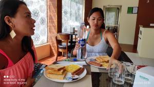 two women sitting at a table with a plate of food at Fali Guest House in Kudahuvadhoo
