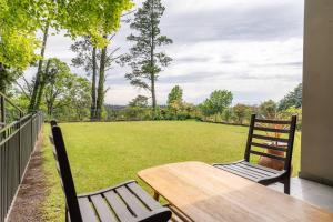 a porch with a wooden table and chairs and a field at Comfort Resort Leura Gardens in Leura