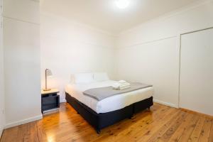 a bedroom with a bed and a lamp on a wooden floor at Comfort Resort Leura Gardens in Leura