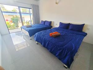 a bedroom with two beds with blue sheets and a window at Vital Point Kampot in Kampot +8 photos
