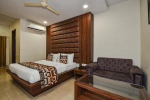 a bedroom with a bed and a couch and a chair at Pineberry Hotels - Near Golden Temple in Amritsar