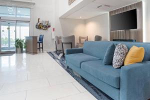 a blue couch in a living room with a tv at Comfort Inn & Suites New Orleans Airport North in Kenner
