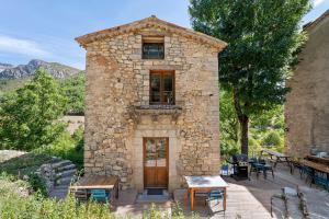 a stone building with tables and chairs in front of it at Gite La Chambrette in Blieux