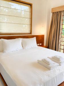 a bedroom with a white bed with two towels on it at Haku - Japandi Village in General Luna