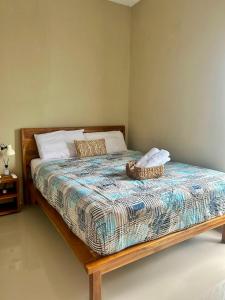 a bed with a wooden frame with a basket on it at Omi Homestay in Praya