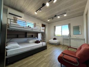 a bedroom with two bunk beds and a chair at GuesthouseKAZE in Miyako-jima