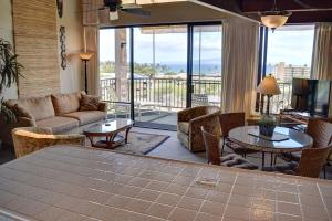 a living room with a couch and tables and a balcony at Kihei Alii Kai D402 in Kihei
