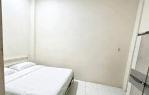a white room with a bed and a mirror at Hotel O Teratays Homestay in Banda Aceh