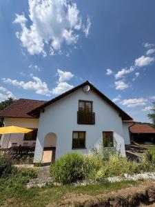 a white house with a blue sky and clouds at Šumavský dům in Drslavice