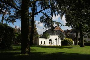 une maison blanche sur une pelouse verdoyante avec des arbres dans l'établissement Gîte de la Conciergerie du Cheval Blanc, à Luttre